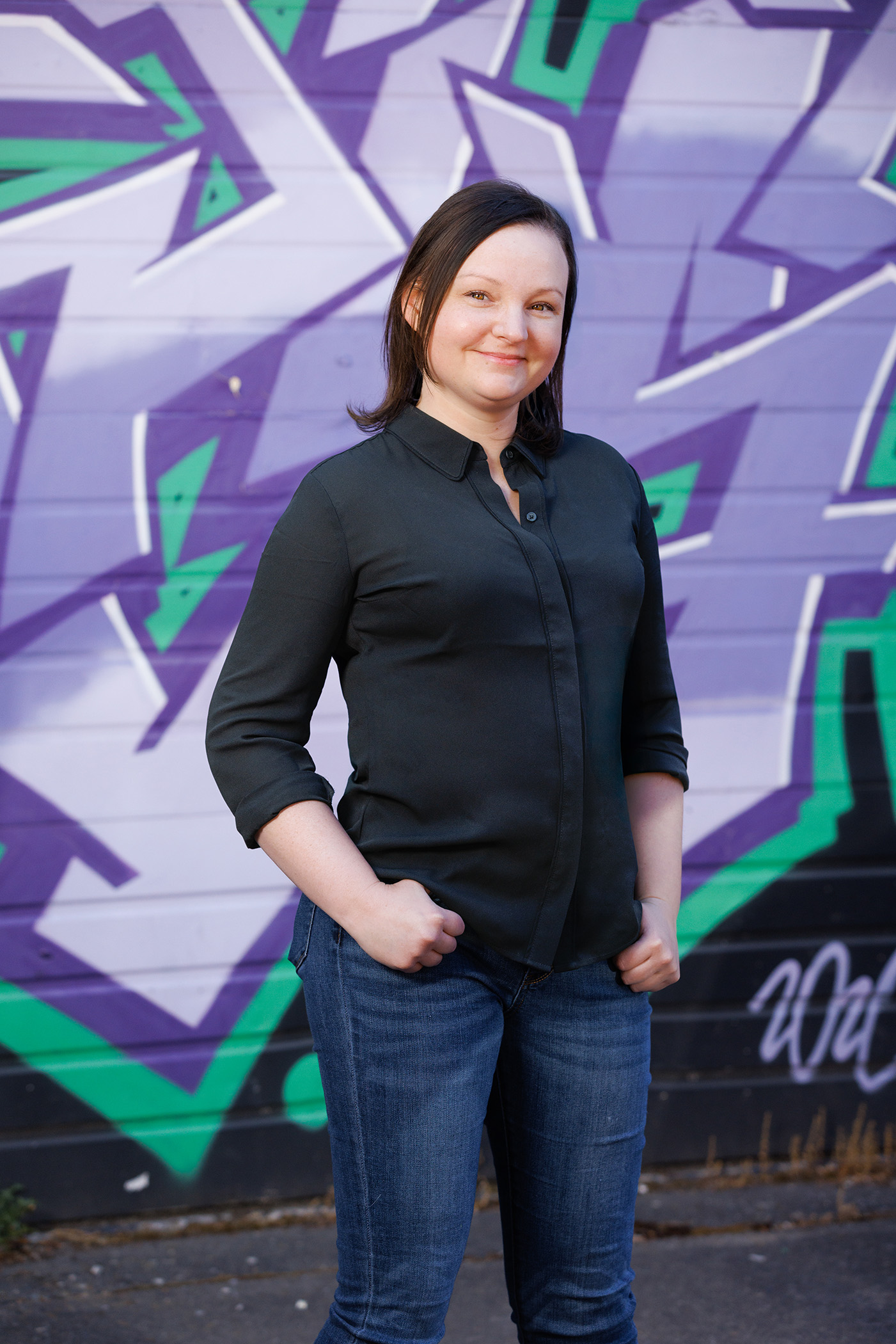 Alyssa posing in front of a graffiti wall.